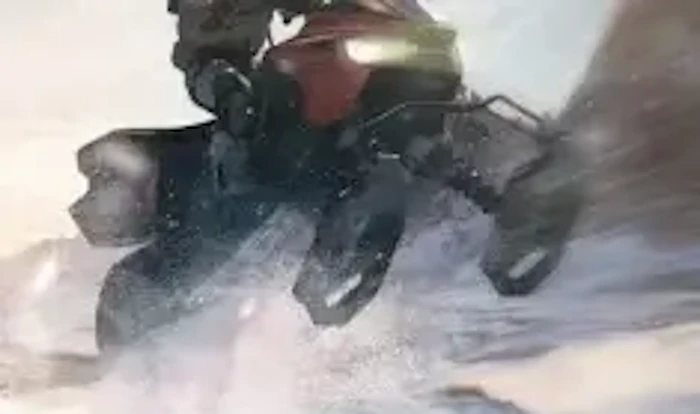 A person rides a snowmobile through thick snow